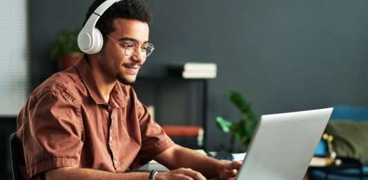Student with headphones typing on student laptop